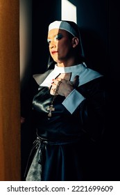 Cross Dressing Drag Queen Performing A Praying Catholic Nun Illuminated By A Ray Of Light - Vertical Picture