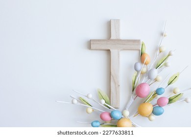 Cross with Easter eggs on a white background with copy space 