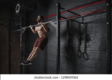 Cross fit athlete doing pull-ups at the gym. Practicing calisthenics. Handsome man doing functional training. 
  - Powered by Shutterstock