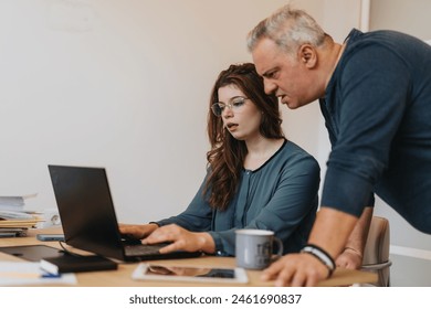 A cross generational team of colleagues collaborating in a startup office, discussing tasks, solving problems, and working together to achieve growth and profitability.