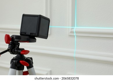 Cross Line Laser Level On Tripod In Front Of White Wall