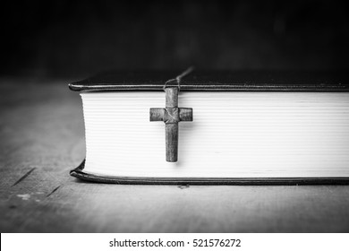 Cross On The Bible On A Wooden Background. Holy Book. Black And White Photography