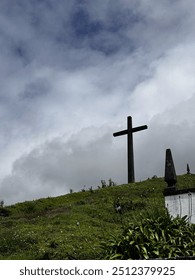 Cross on a hill with clouds behind 