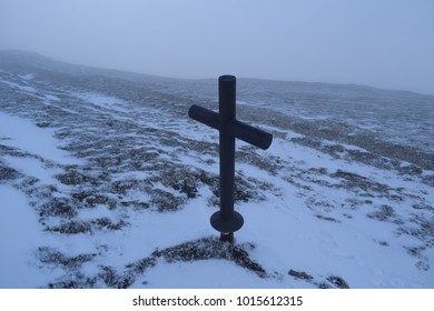 cross on icy mountain in the winter season