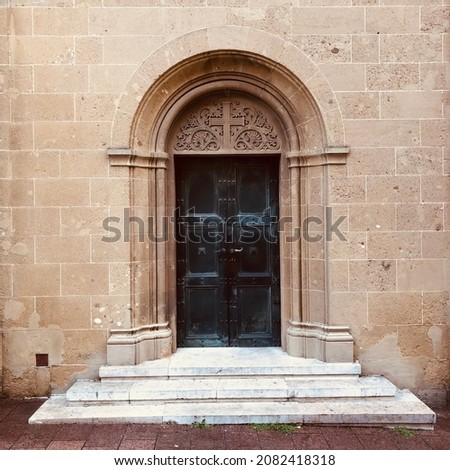 with cross on metal single arm church door and 3 stairs and magnificent big block bricks around facade