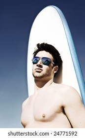 Cross processed image of a surfer at the beach with waves reflecting in his sunglasses