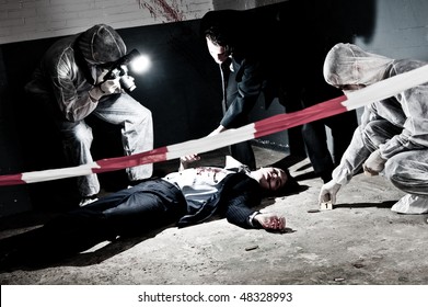 A cross processed murder scene with two forensic team investigating a crime on a businessman in a basement