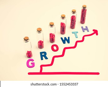 Cross processed tone effect. Multicolored wooden alphabet of growth text on light yellow color background with small glass bottles, vivid or vibrant red gravel and drawing red graph steps. 