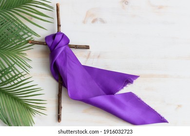cross with purple sash and palms on white wood - Shutterstock ID 1916032723