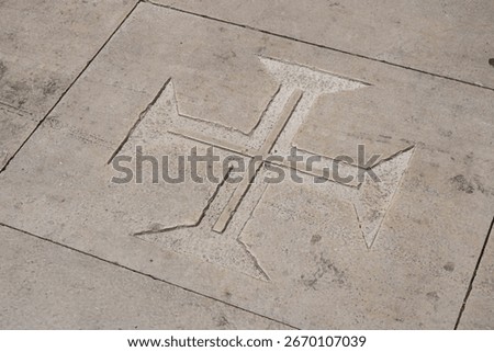 The cross pattée, sometimes called the Templar cross, and most often nicknamed the Maltese cross, carved into a concrete floor