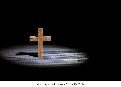 the cross stands on a dark wooden background in a ray of light in the dark - Shutterstock ID 1337957132