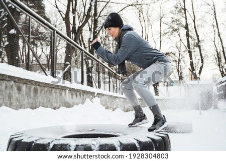 Cross training outside. Athletic woman during her outdoors winter workout with a tire.