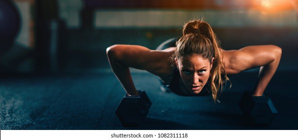 Cross training. Young woman exercising with dumbbells