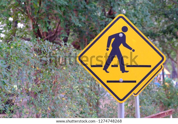 A cross walk sign on steel pole with green nature\
background 