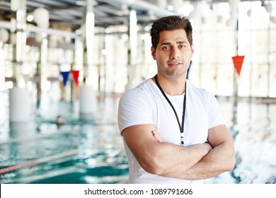 Cross-armed man in activewear looking at camera while having break between trainings by swimming-pool - Powered by Shutterstock