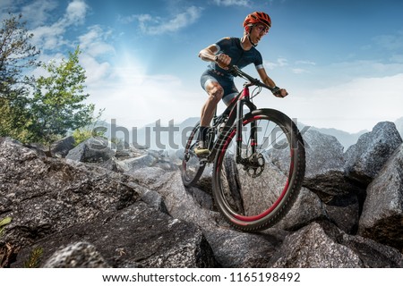 Cross-Country biker on stone trail. Male cyclist rides the rock