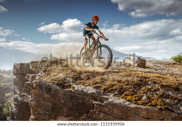 Cross-Country\
biker on trail. Male cyclist rides the\
rock