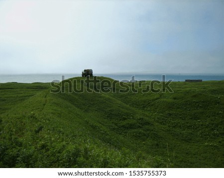 cross-country motor home among green hills against the sea and blue sky in summer