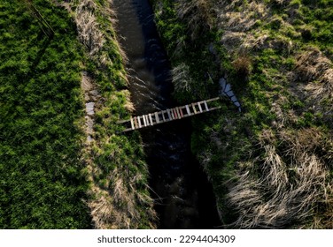 cross-country run through a flooded stream. footbridge with a thinly spaced plank floor. Big water in a narrow channel, video flight over the landscape. seed congestion - Powered by Shutterstock