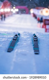 Cross-country Ski Are Ready Beafore Race On The Ground In The Start. Night Light, Snow On The Ground And Blurred Light In The Background.