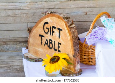 Crosscut Section Of A Tree Says Gift Table To Label Things With A Sign At The Wedding Ceremony Of A Bride And Groom.