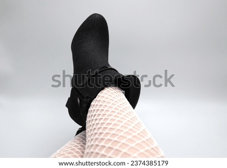 Crossed female legs with white stay ups stockings and black high heel shoes on white background