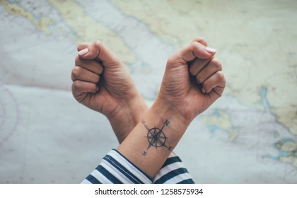 Crossed Fists With Compass Tattoo On One Ankle. Travel Concept