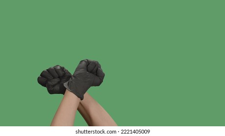 Crossed hands in black gloves with clenched fists raised for protest on green screen. Cropped shot of protester raising arm clenching fist at political demonstration. Concept of revolution or protest. - Powered by Shutterstock