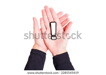Crossed hands holding a large black and white exclamation mark symbol isolated on white background. Expression of strong emotions or opinions, sense of urgency and importance.