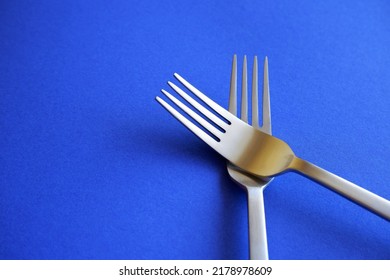 crossed silver forks on a blue tablecloth background