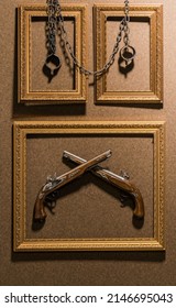 Crossed Vintage Pistols And Vintage Iron Shackles Hang On The Wall In Frames