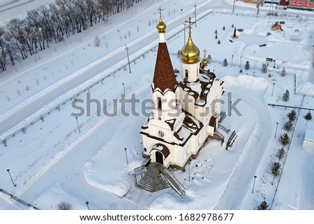 Crosses of the temple of Princess Olga in the background of the setting sun of a clear winter night in the whirling white snow taken from the height of bird flight for a quadcopter (copter, drone)