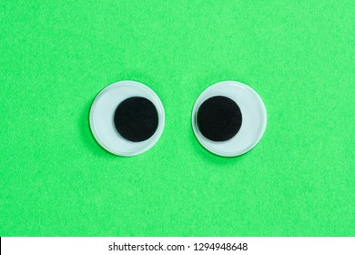 Cross-eyed Googly Eyes On Neon Green Background, Mad Funny Toys Eyes Close-up.