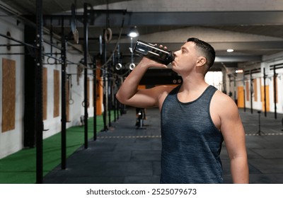 A CrossFit athlete rehydrates after an intense training session. The gym is equipped with functional fitness tools, supporting strength and endurance. - Powered by Shutterstock