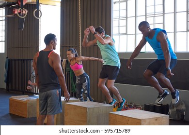 Crossfit Class Jumping On Wooden Boxes Guided By Trainer, Strength Training Fitness Workout In Gym