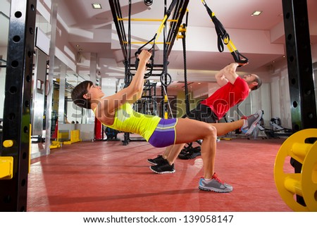 Crossfit fitness TRX training exercises at gym woman and man push-ups workout