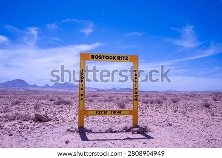 Crossing the parallel: a weathered sign marks the Tropic of Capricorn deep within the arid heart of Namibia. This isolated marker defines the northernmost latitude where the sun appears directly overhead, anchoring a remote point on the planet's vast desert canvas.