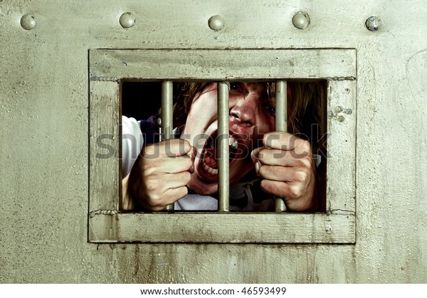 Cross-processed image of a man going\
insane, grabbing the bars of his jail cell, looking rabid and\
screaming\
uncontrollably