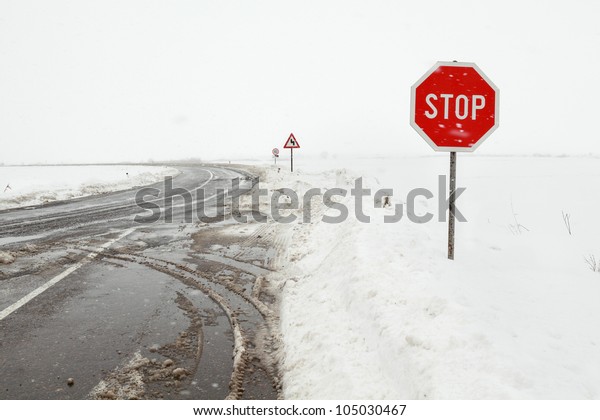 Crossroad in a\
stormy winter day with stop\
sign