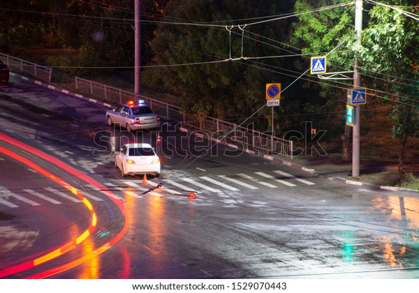 At the crossroads at night, the driver violated\
and knock down a pedestrian. The police draw up a road traffic\
accident. Traffic violation. Police inspector car with emergency\
flashing lights.