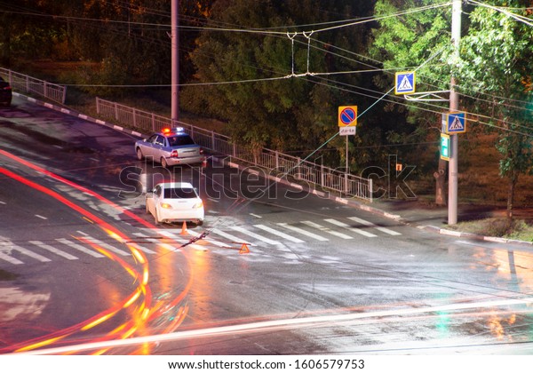 At the crossroads at night, the driver violated\
and knock down a pedestrian. The police draw up a road traffic\
accident. Traffic violation. Police inspector car with emergency\
flashing lights.