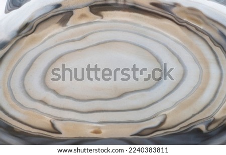 A cross-section of striped flint stone with unique concentric dark and pale stripes rippled across its surface
