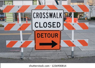Crosswalk closed and detour signs on the barricade blocking the intersection.