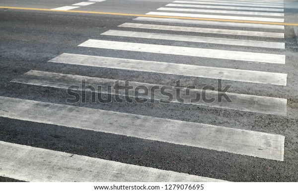 crosswalk on the road for safety when\
people walking cross the street, Pedestrian crossing on a repaired\
asphalt road, Crosswalk on the street for\
safety.