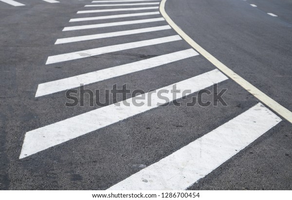crosswalk on the road for safety when\
people walking cross the street, Pedestrian crossing on a repaired\
asphalt road, Crosswalk on the street for\
safety.