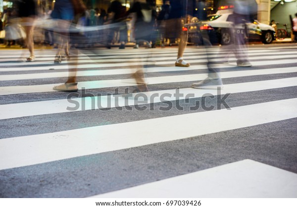 Crosswalk and\
pedestrian at modern city zebra crossing street with fast moving\
car lights in the Shibuya\
Crossing