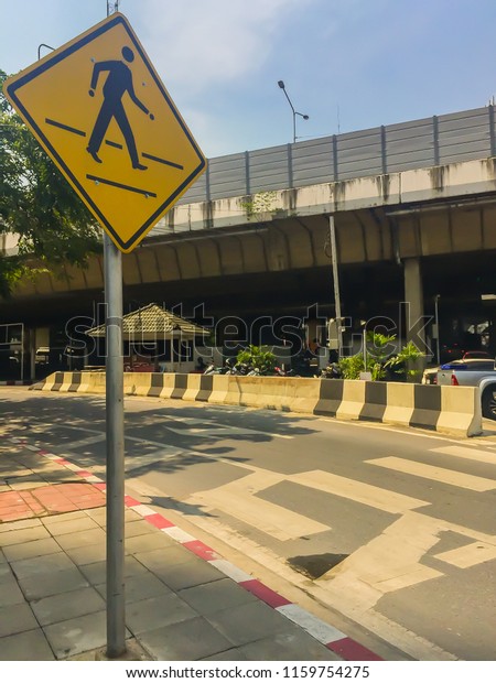 Crosswalk sign at the junction road. Black and\
white crosswalk stripped on the asphalt road at the junction of\
city for safety