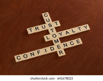 Crossword Puzzle With Words Trust, Loyalty, Confidence. Customer Loyalty Concept. Ivory Tiles With Capital Letters On Mahogany Board.