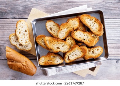 Crostini, Crusty baguette slices toasted with olive oil, on a baking tray. Top view. - Powered by Shutterstock