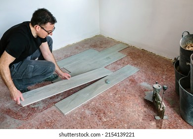 Crouched bricklayer placing tiles to install a floor
